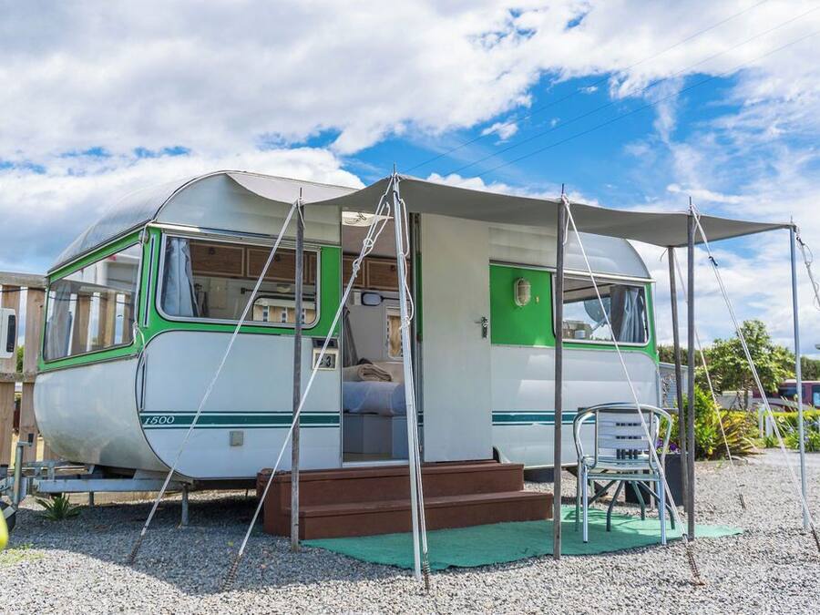 Uma casa de camper vintage com entrada coberta, um pequeno alpendre e um degrau para entrar.