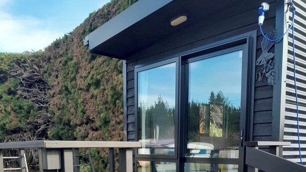 A modern building with a wooden deck and large glass doors. - Leithfield Beach Holiday Park (Leithfield)