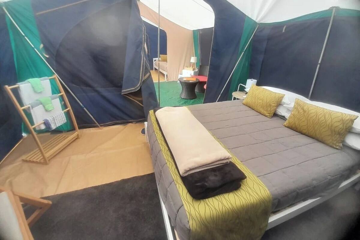 Um quarto com tenda, uma cama, uma mesinha e uma cadeira.
