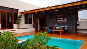 A swimming pool with wooden decking, a pergola, and a stone wall. - Stunning Villa Sant Luis with Heated Pool, Close to Playa de Ugán in (Pájara)