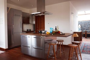 Eine moderne Küche mit Edelstahlgeräten, Holzhocker und Blick auf eine felsige Landschaft.