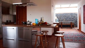 Una cucina moderna con elettrodomestici in acciaio inossidabile, un'isola centrale con sgabelli e vista su un paesaggio roccioso attraverso un'ampia finestra.