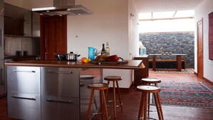 Une cuisine moderne dotée d’appareils électroménagers en acier inoxydable, d’un îlot central avec des tabourets et offrant une vue sur un paysage rocheux grâce à une grande fenêtre.