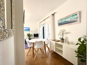 A dining area with a round table and chairs, a television, and a potted plant.