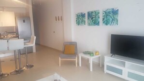 A modern living room with a flat-screen TV, a white coffee table, and a seating area with a chair and a sofa. - Annalara I - Bahamas - Tenerife (Bajamar)