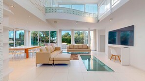 A spacious living room with a sectional sofa, a dining area, and a large TV.
