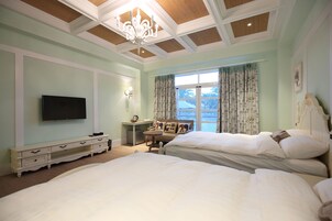 Habitación de hotel con dos camas, televisión, escritorio y ventana con cortinas.