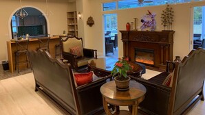 A spacious living room with a fireplace, comfortable seating, and a view of the outdoors. - Serrado Manor (Ji'an)