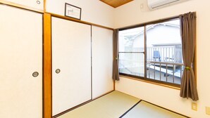 A room with tatami flooring, a sliding door, a window with curtains, and an air conditioning unit. - KAGURAZAKA RETRO BAR & HOTEL (Tokyo)