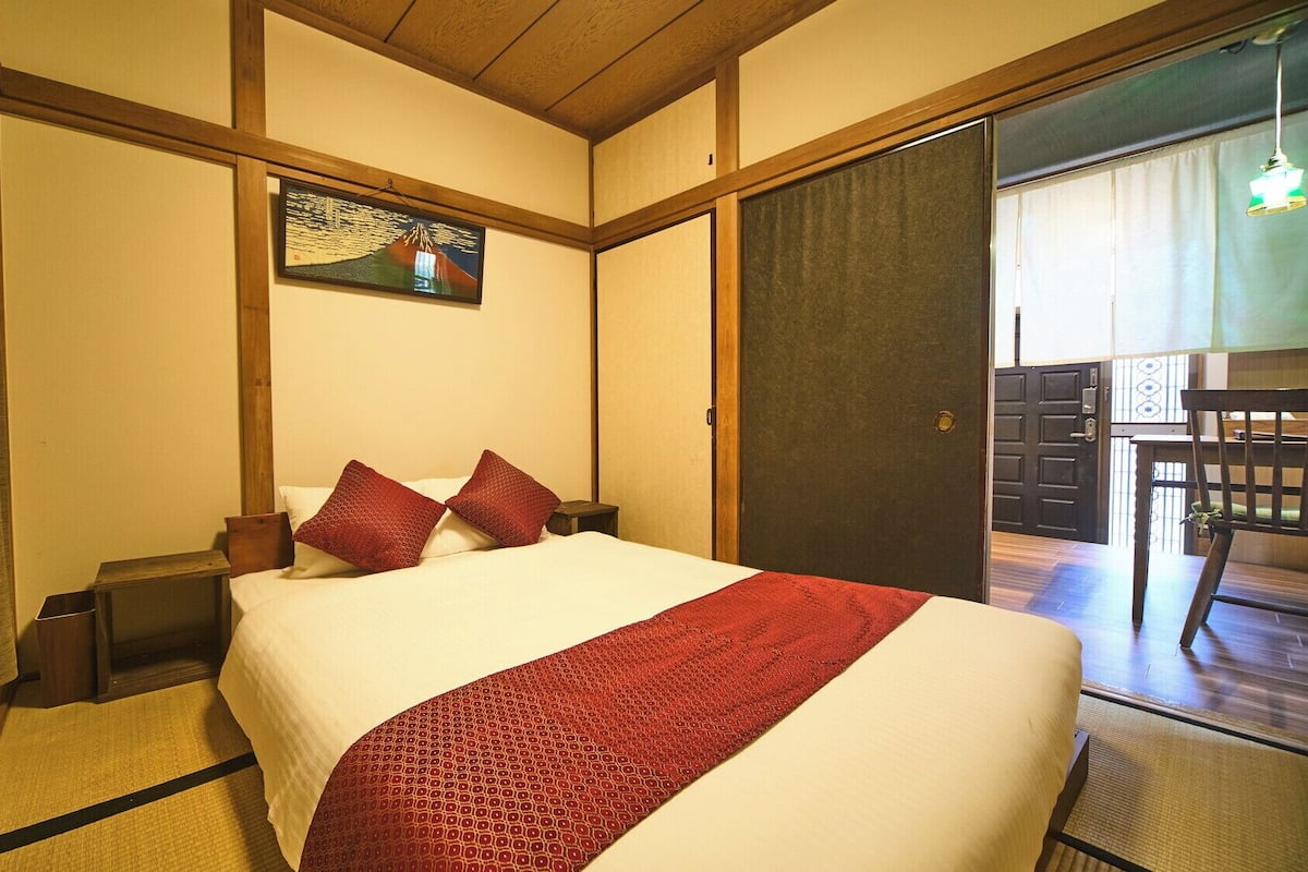 Een hotelkamer met een bed, een schilderij, een houten plafond en een deur die uitkomt op een balkon.