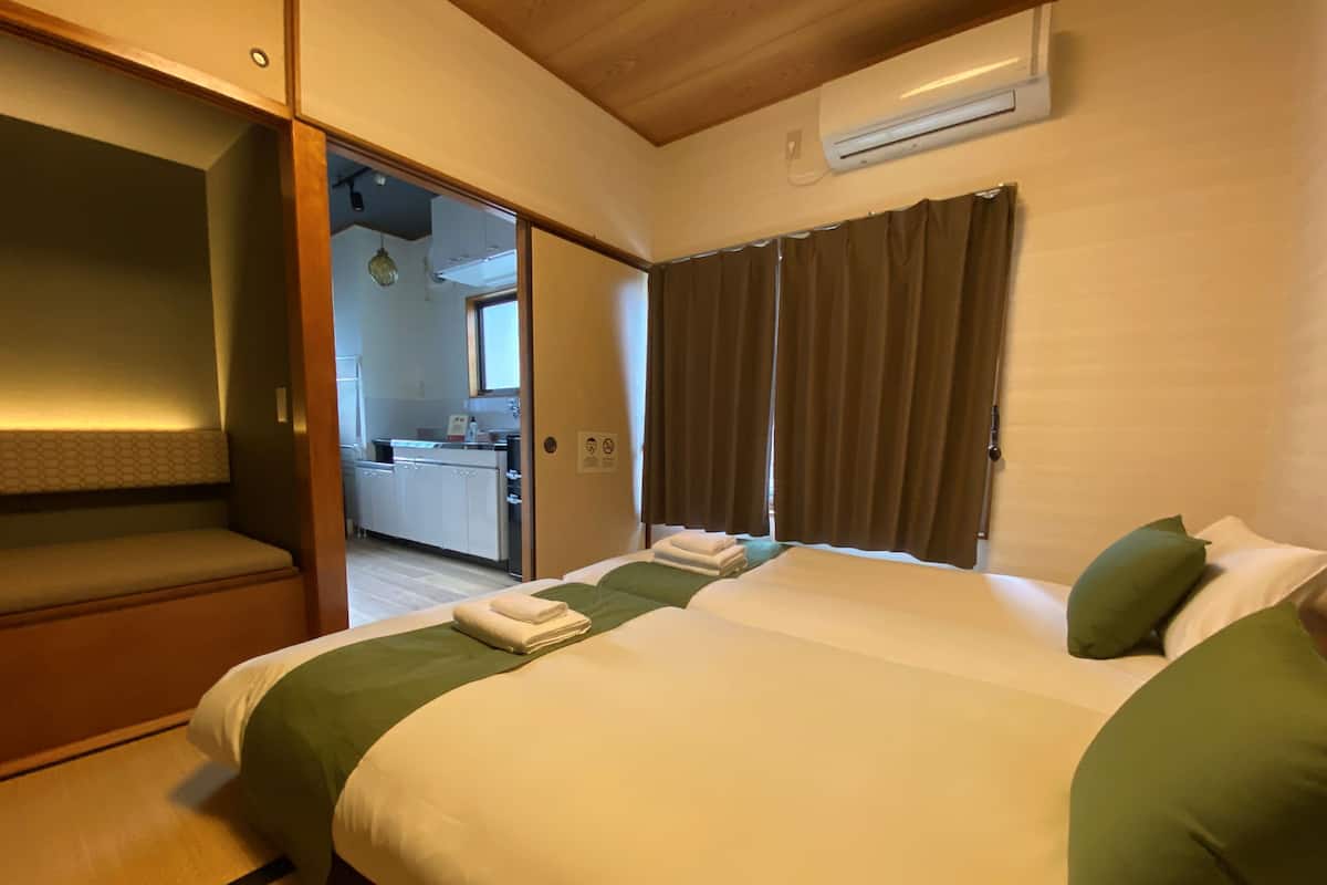 Een hotelkamer met een bed, een bankje, een airconditioning en uitzicht op de keuken en badkamer.
