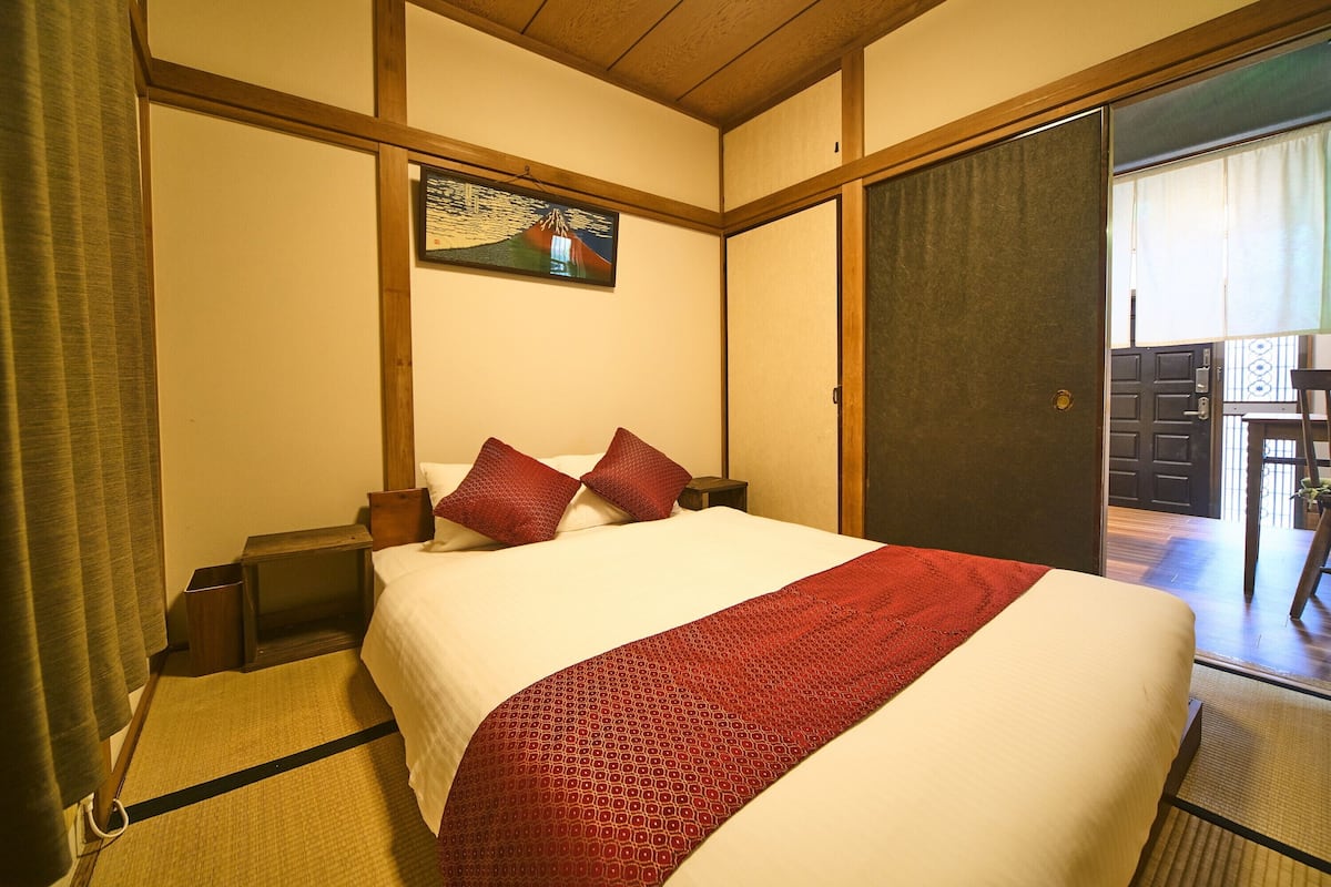 Hotelkamer met een bed, een houten hoofdbord, een schilderij aan de muur en een schuifdeur naar een balkon.