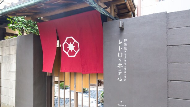 A hotel entrance with a red curtain featuring a white logo, a gray wall with Japanese text, and a small sign indicating "Room 1". - KAGURAZAKA RETRO BAR & HOTEL (Tokyo)