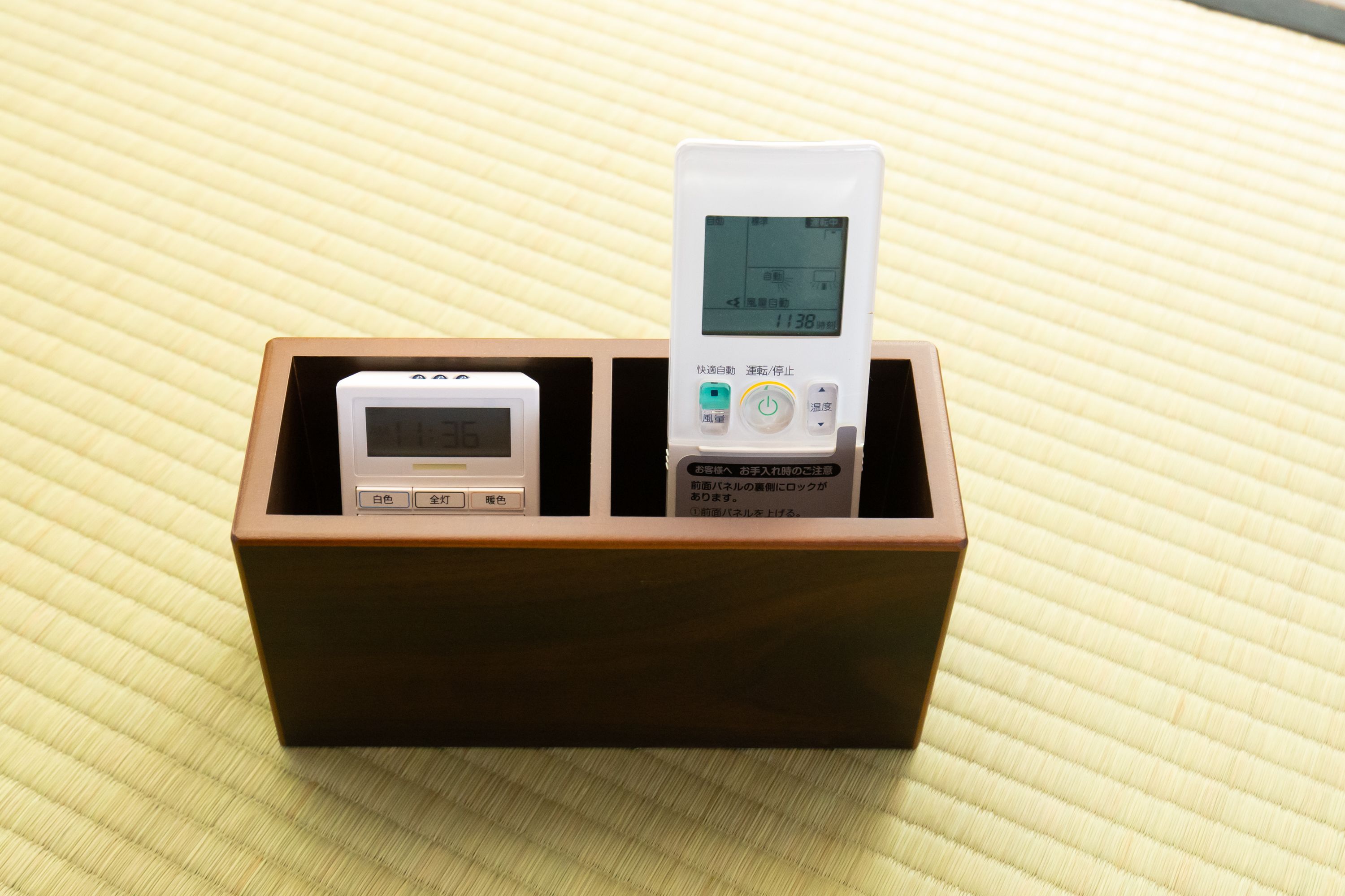 A wooden box containing two electronic devices with screens and buttons, placed on a textured surface.