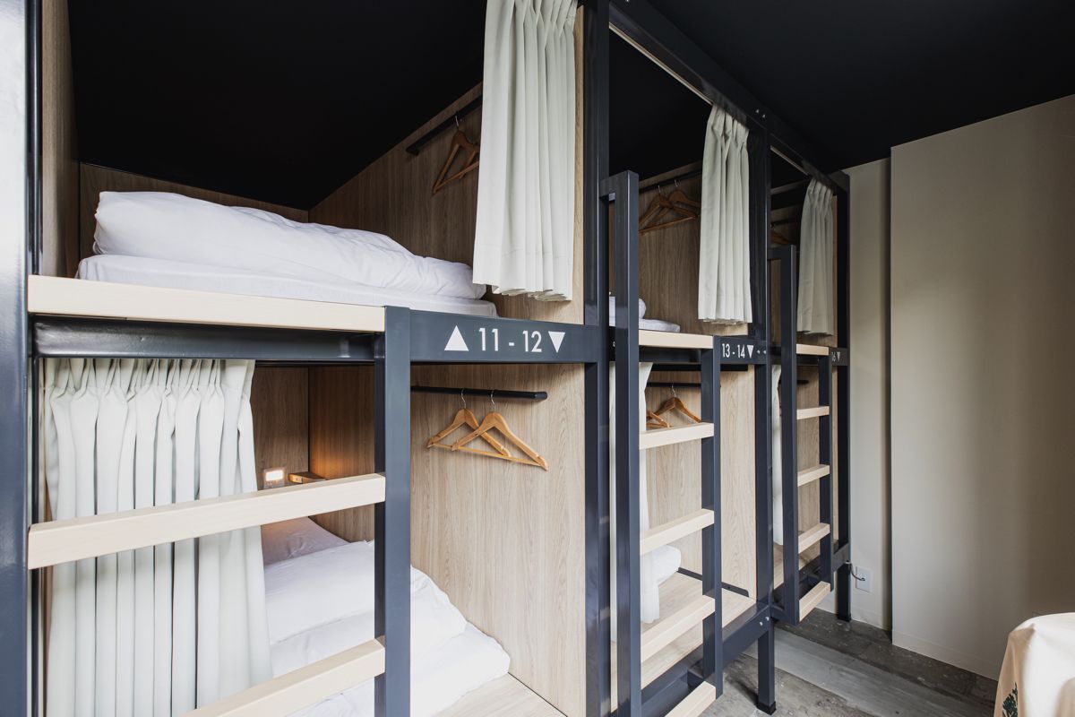Un dormitorio con literas, paredes de madera y una escalera de metal negro.