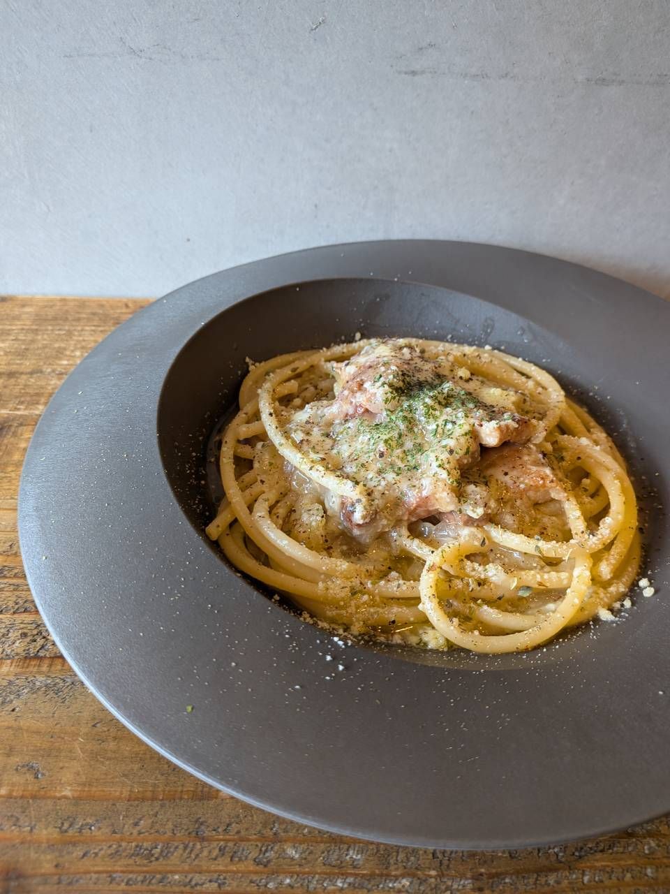 A plate of spaghetti with a topping of cheese and herbs.