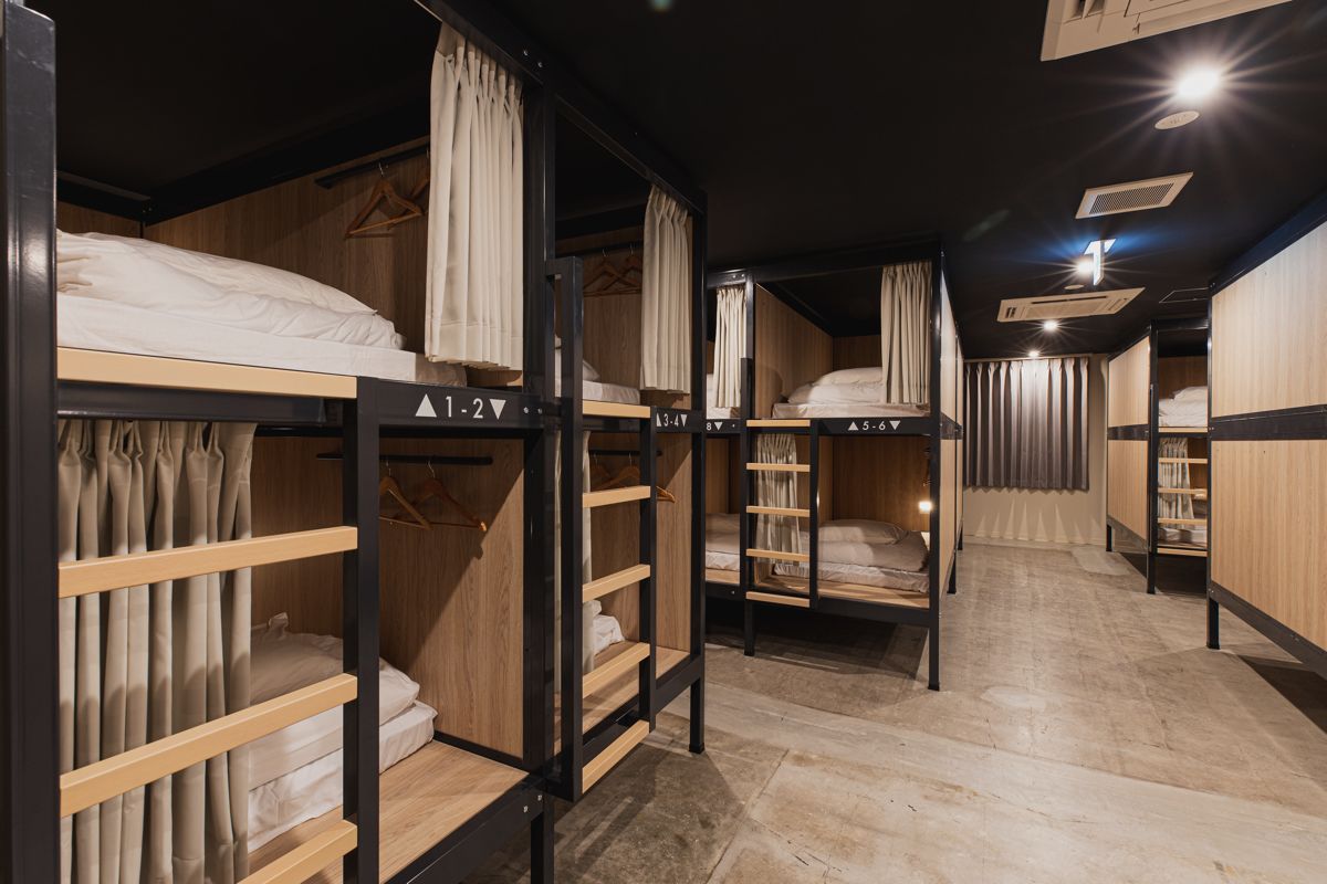 Habitación de hotel con literas, cabeceros de madera y cortinas.