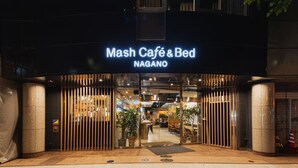 Exterior do Mash Café & Bed Nagano, com entrada moderna, portas de vidro, plantas em vasos e interior visível através do vidro.
