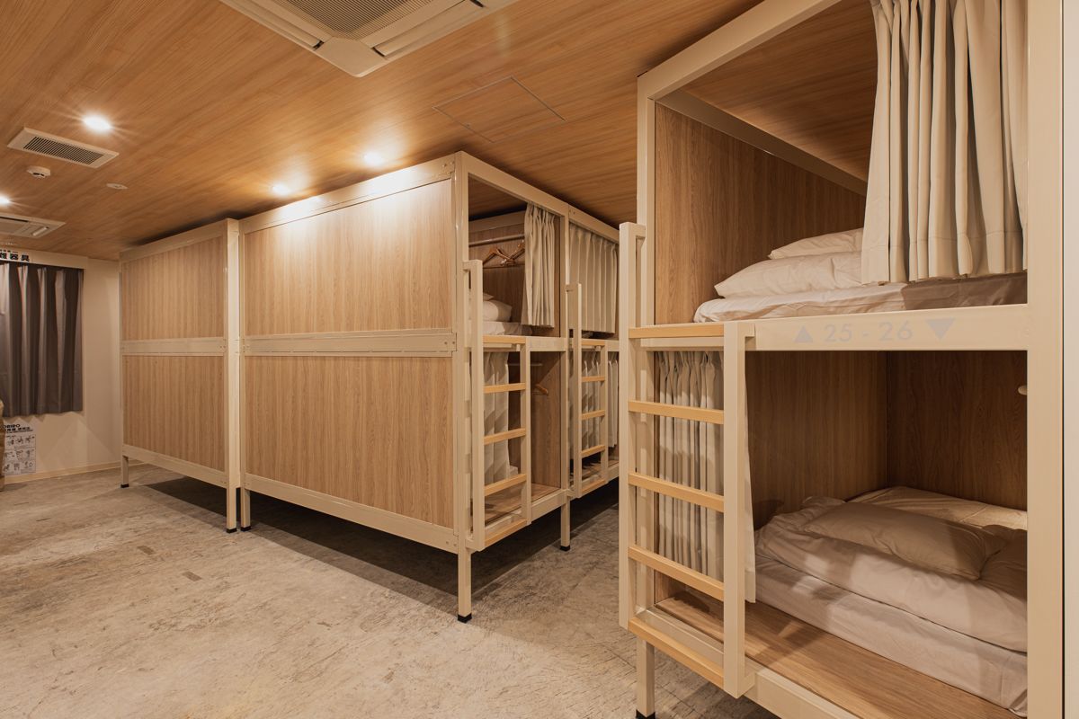 A room with bunk beds, wooden wardrobe, and a ladder.