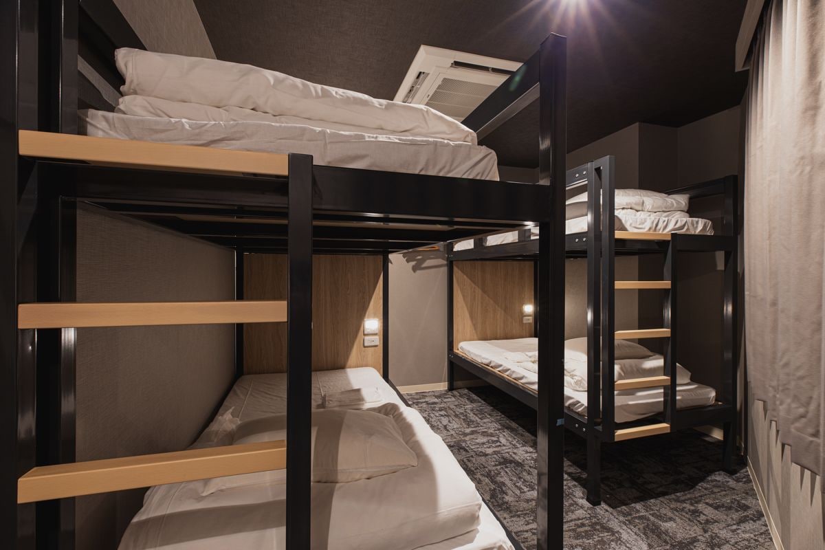 A bunk bed room with a window, a door, and a carpeted floor.