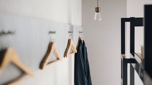 Um quarto com um cabideiro de madeira, um lustre pendente e uma cadeira preta.
