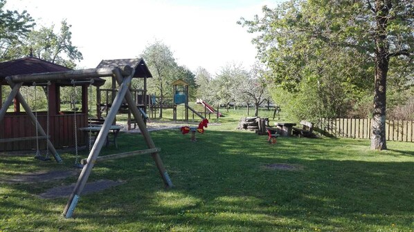 Ein Spielplatz mit Schaukeln, einer Rutsche und einer Kletteranlage.
