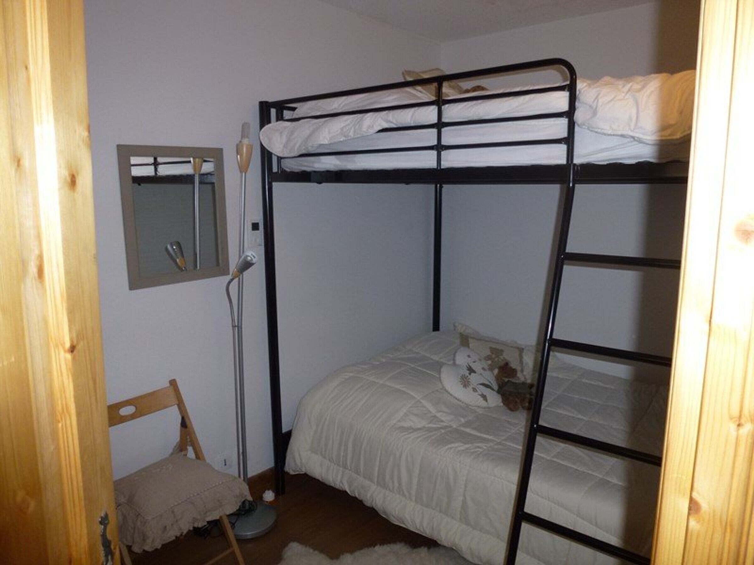 Quarto com beliche, espelho, cadeira e aquecedor.