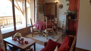 Una sala de estar acogedora con un sofá rojo, una mesa de comedor con sillas y un aparador de madera.