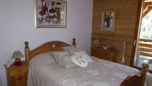 Una cama de madera con un cojín con forma de corazón, una mesita de noche con una lámpara y un cuadro en la pared.