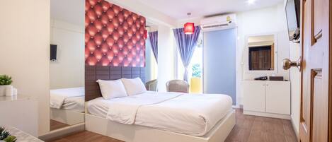 A modern bedroom with a large bed, a mirror, a wardrobe, and a TV.