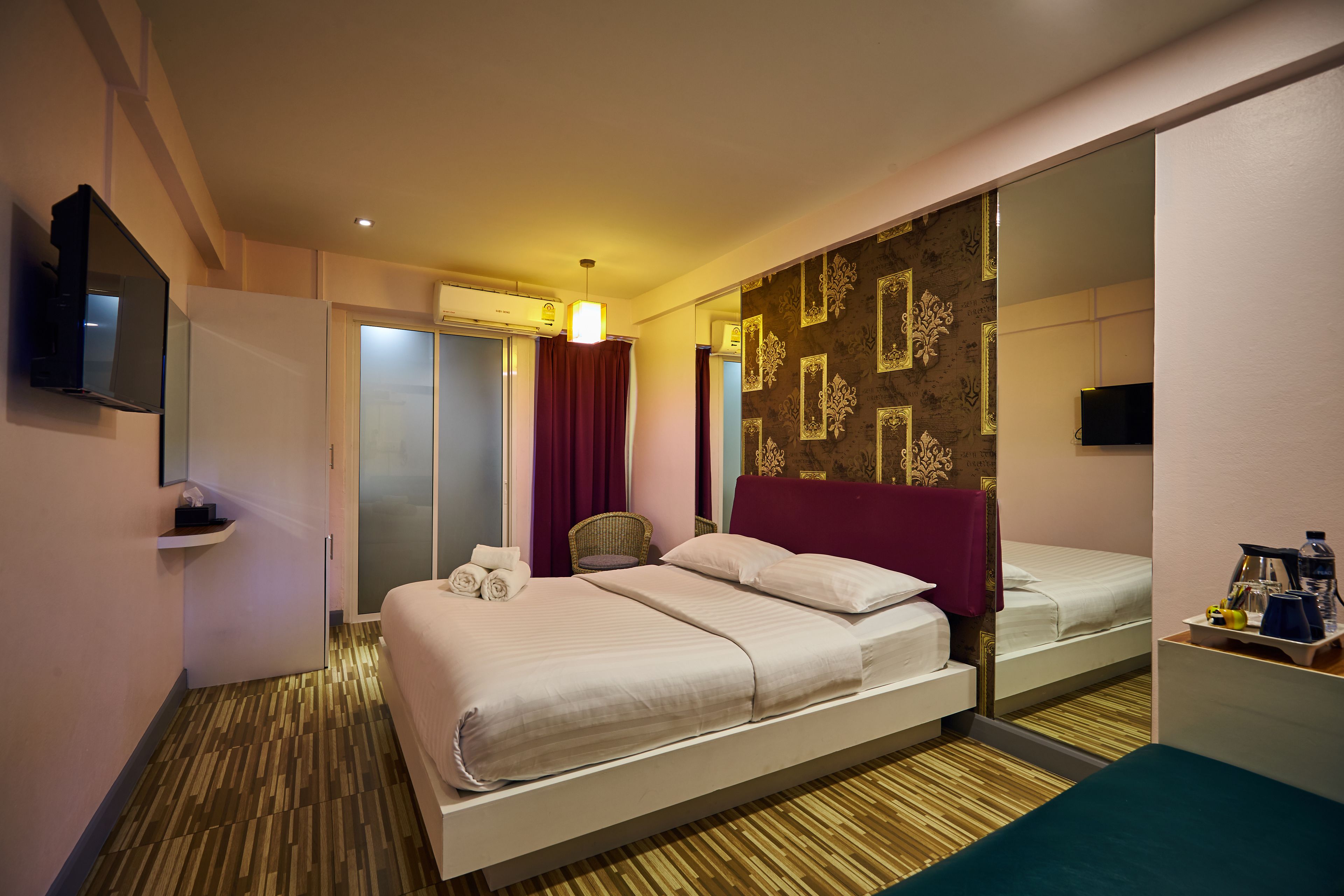 Une chambre d’hôtel avec un grand lit, un miroir, une télévision et une petite table avec des articles de toilette.