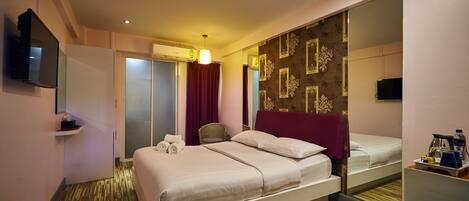 Ein Hotelzimmer mit einem großen Bett, einem Spiegel, einem Fernseher und einem kleinen Tisch mit Toilettenartikeln.