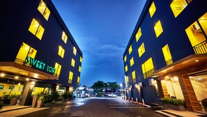 Un hotel con un cartel que dice 'Sweet Love', varios balcones y una entrada bien iluminada.