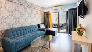 Una sala de estar moderna con un sofá azul, una mesa de centro de vidrio y una mesita auxiliar con un jarrón de flores.