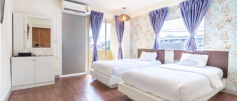 Une chambre moderne avec deux lits simples, une armoire et une grande fenêtre avec des rideaux.