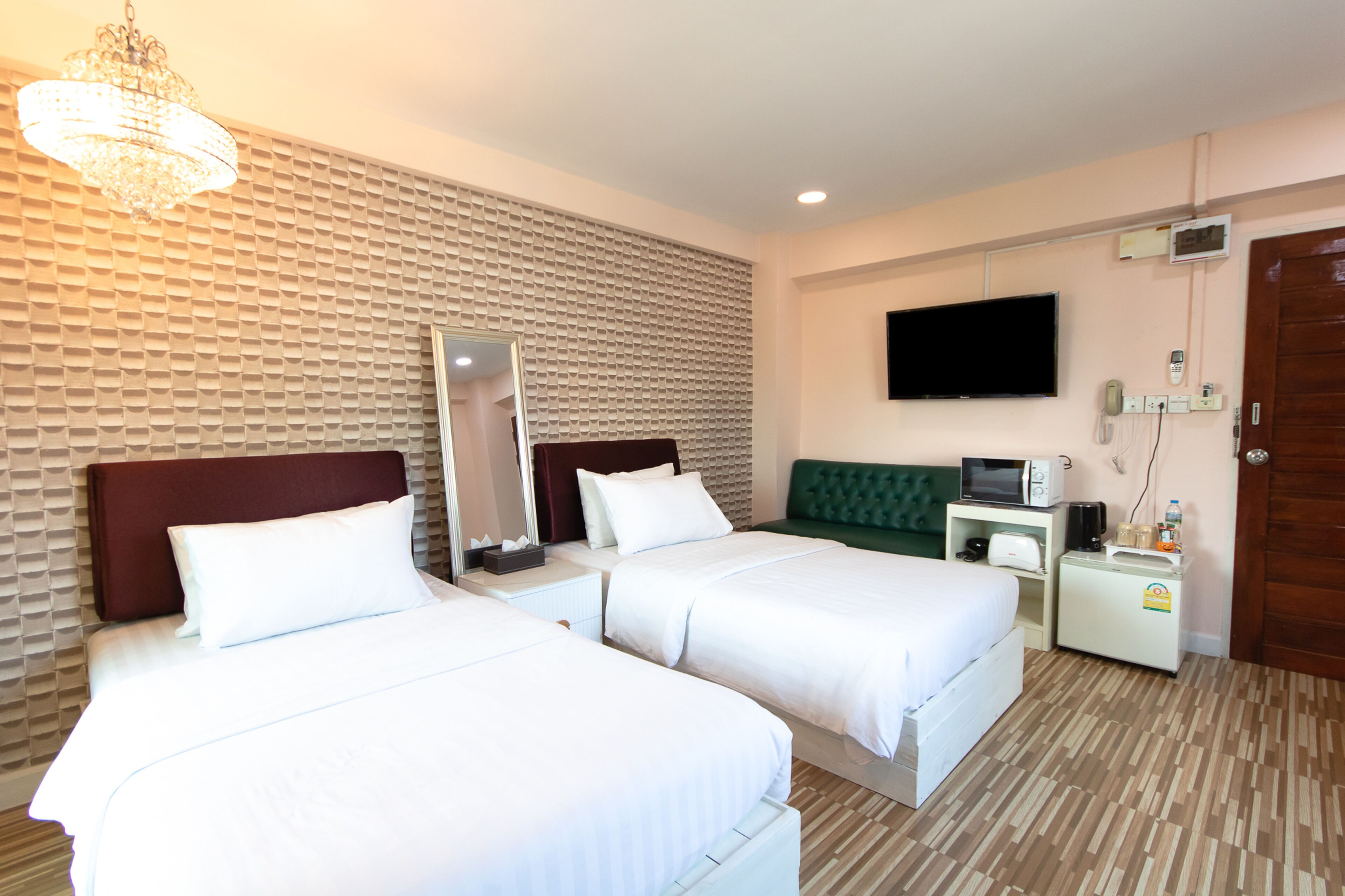 Habitación de hotel con dos camas, televisión, microondas y refrigerador pequeño.