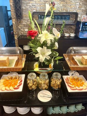 A buffet setup with various food items and a floral centerpiece. - Sweetloft Hotel Don Muang (Bangkok)