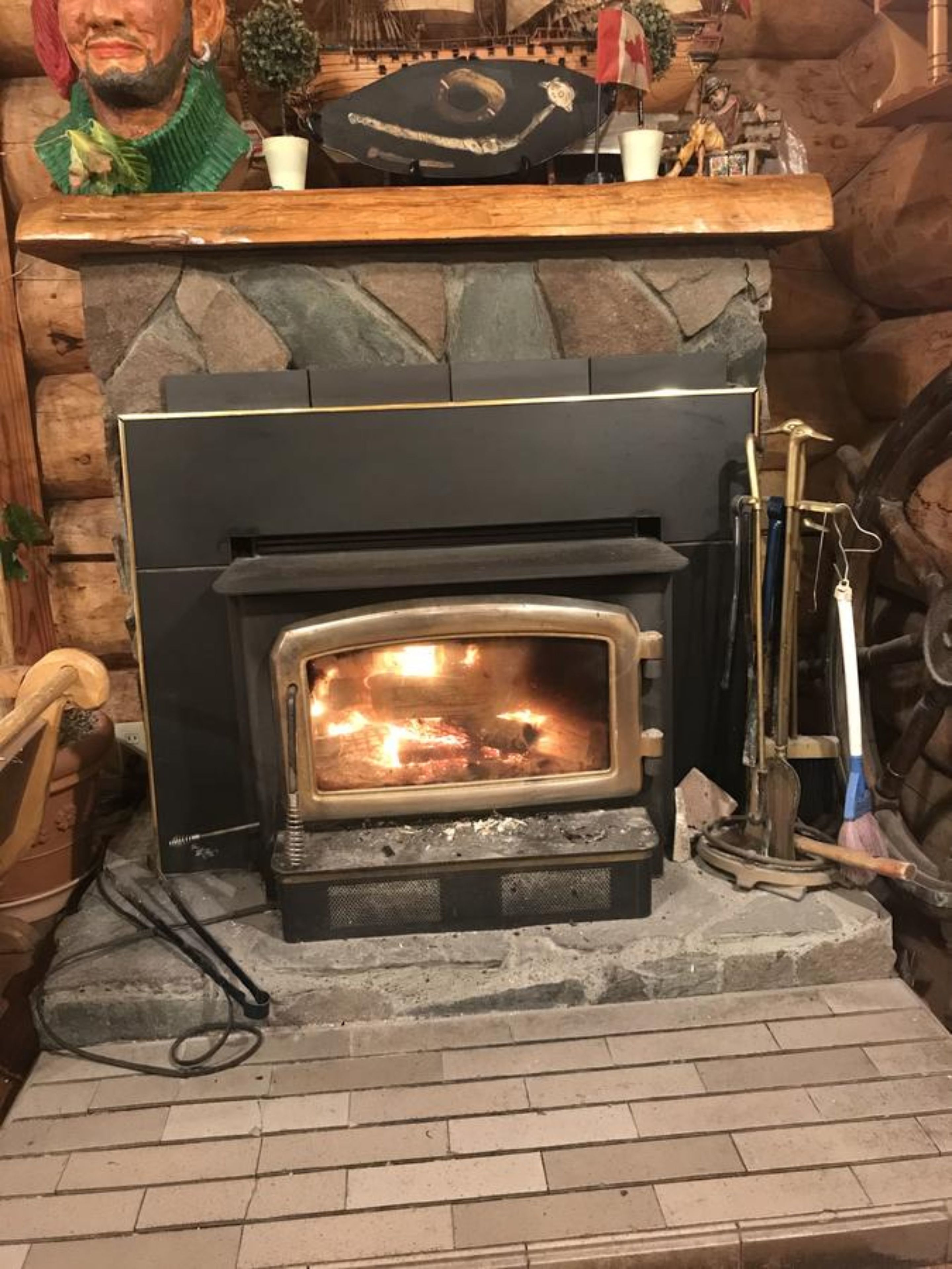 A stone fireplace with a visible fire, a wooden mantel, and a rustic interior.