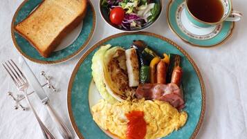Prato de café da manhã com torradas, ovos mexidos, bacon, legumes grelhados e uma salada.