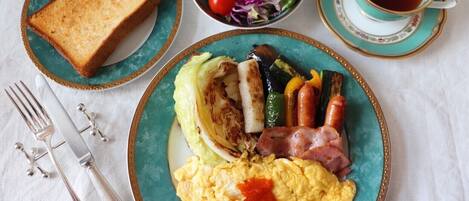 A breakfast plate with toast, scrambled eggs, bacon, grilled vegetables, and a side salad.