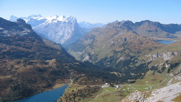 Eine Berglandschaft mit einem See, einer kleinen Siedlung und einem klaren Himmel.