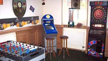 Una habitación con mesa de futbolín, dardos y un jukebox.
