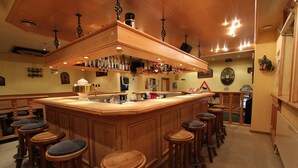 Eine Bar mit Holzhockern, einer Theke und verschiedenen Flaschen und Gläsern.