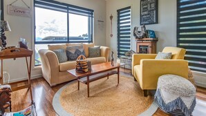 Una sala de estar con un sofá color beige, un sillón amarillo, una mesita de centro y un tapete redondo.