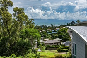 A residential area with houses, lush greenery, and a view of the sea with boats.