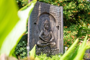 A stone Buddha statue in a garden setting.
