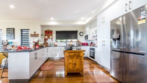 Una cocina moderna con armarios blancos, un refrigerador de acero inoxidable, una isla central de madera y una alfombra roja.