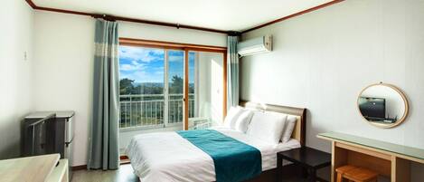 A hotel room with a bed, a desk, a chair, a TV, and a window with a view of the outdoors.