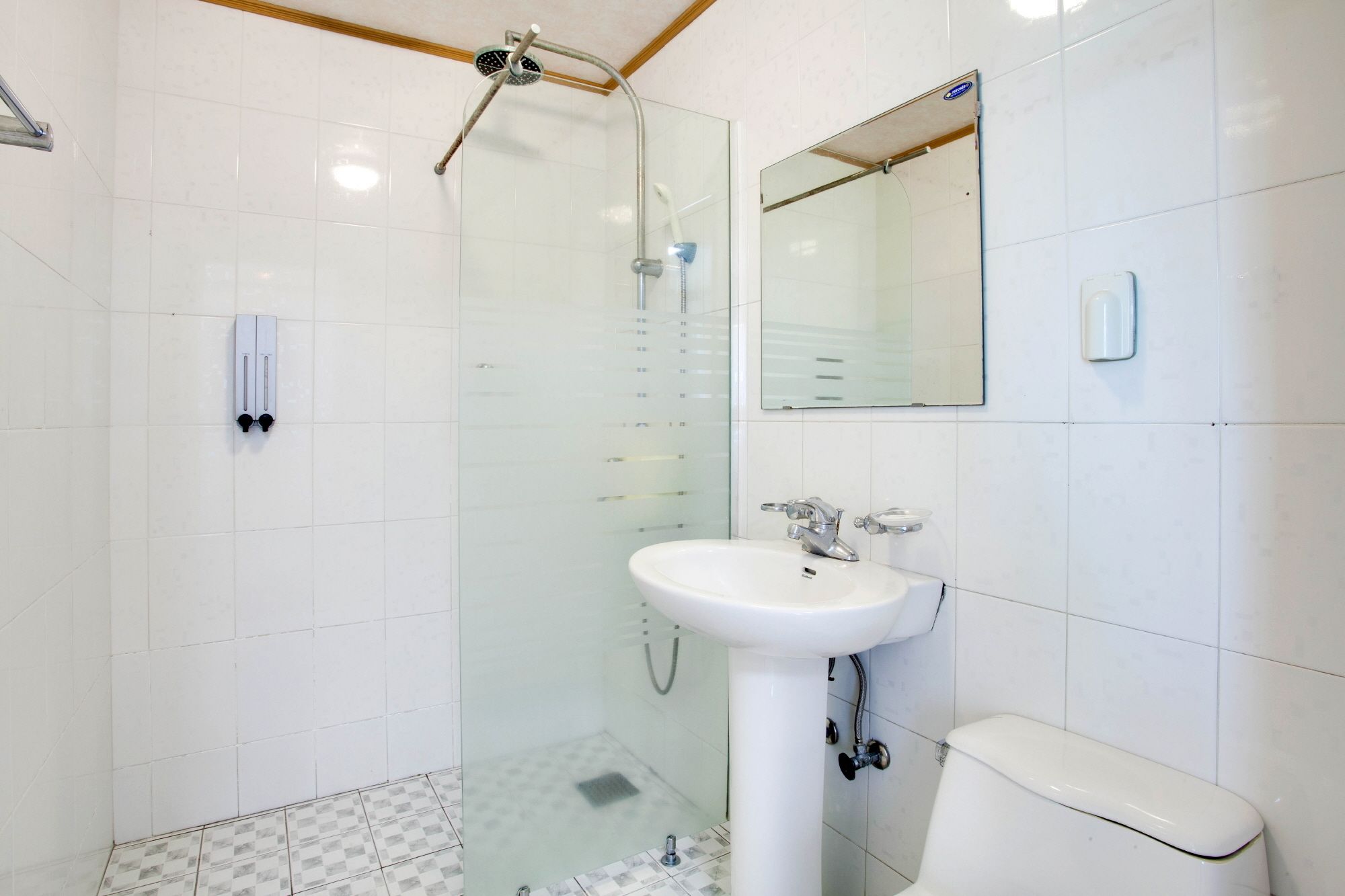 Un baño con cabina de ducha de vidrio, un lavamanos blanco y un inodoro.