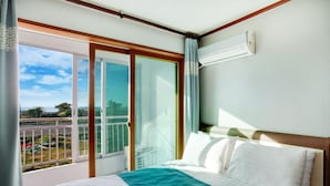 Une chambre d’hôtel avec un lit, un balcon offrant une vue et un appareil de climatisation.